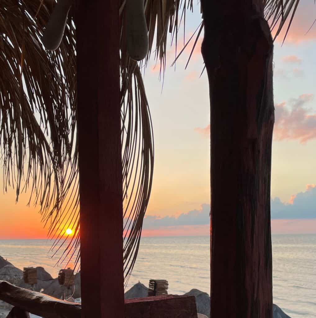 vibrant sunset setting in on the beach shoreline in Isla Holbox, one of the cheapest beach towns in Mexico to visit