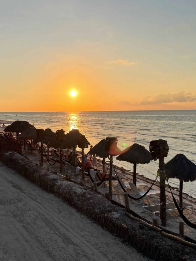 beach shoreline featuring several palapas during sunset in Isla Holbox, Mexico