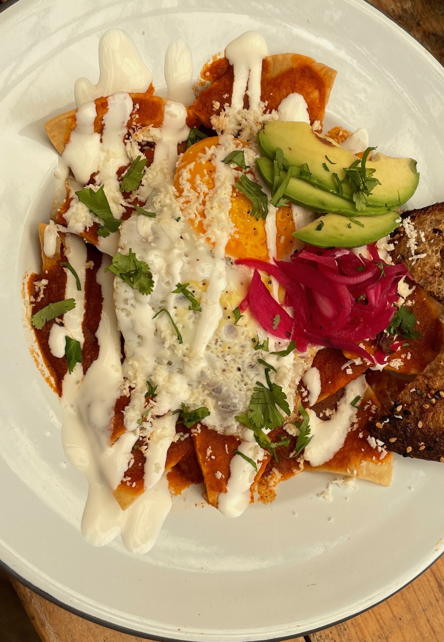 plate of Chilaquiles with a spicy red sauce, a classic Mexican breakfast being served at Bonitas Burger in Tulum