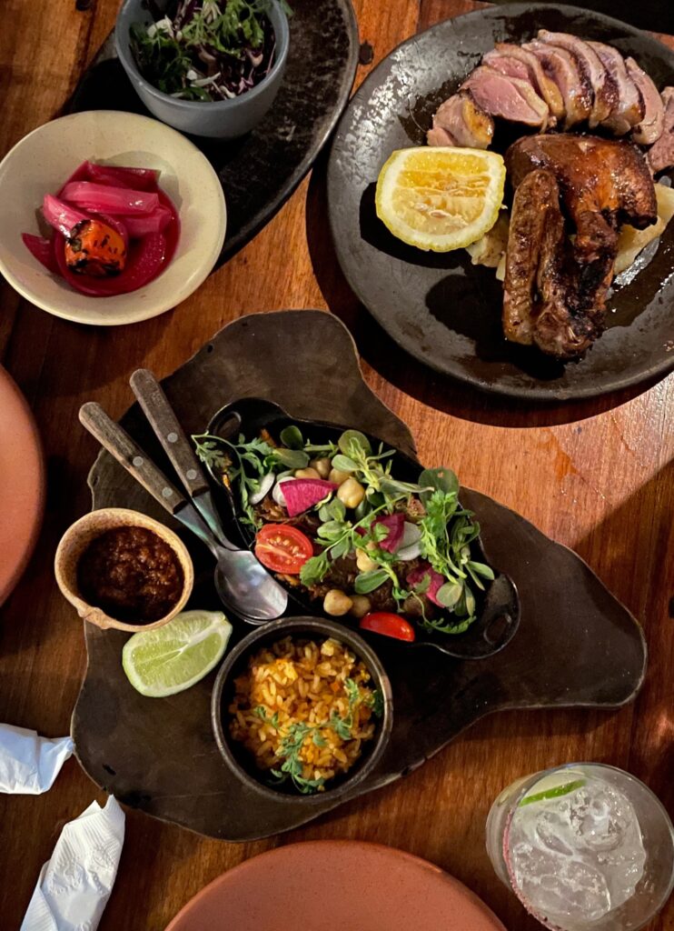 table full of various mexican meat dishes including duck and lamb