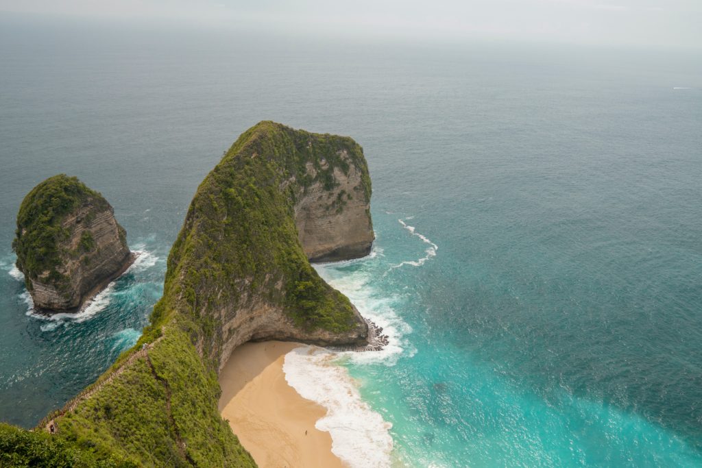 stunning blue waters in the ocean with massive rock placed into the water at Kelingking beach nusa penida indonesia 