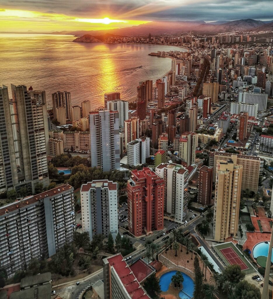 a bright orange sunset pealing through the skies in the late evening along the seaside in Benidorm, Spain