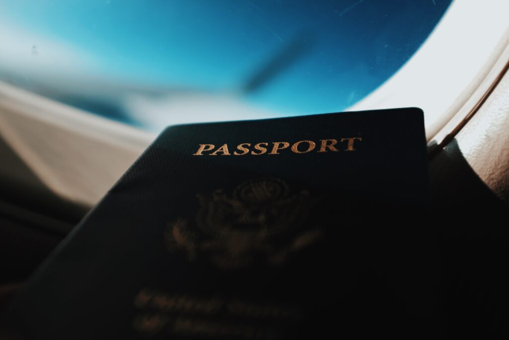 photo of passport on a plane with airplane window in the background showing blue skies