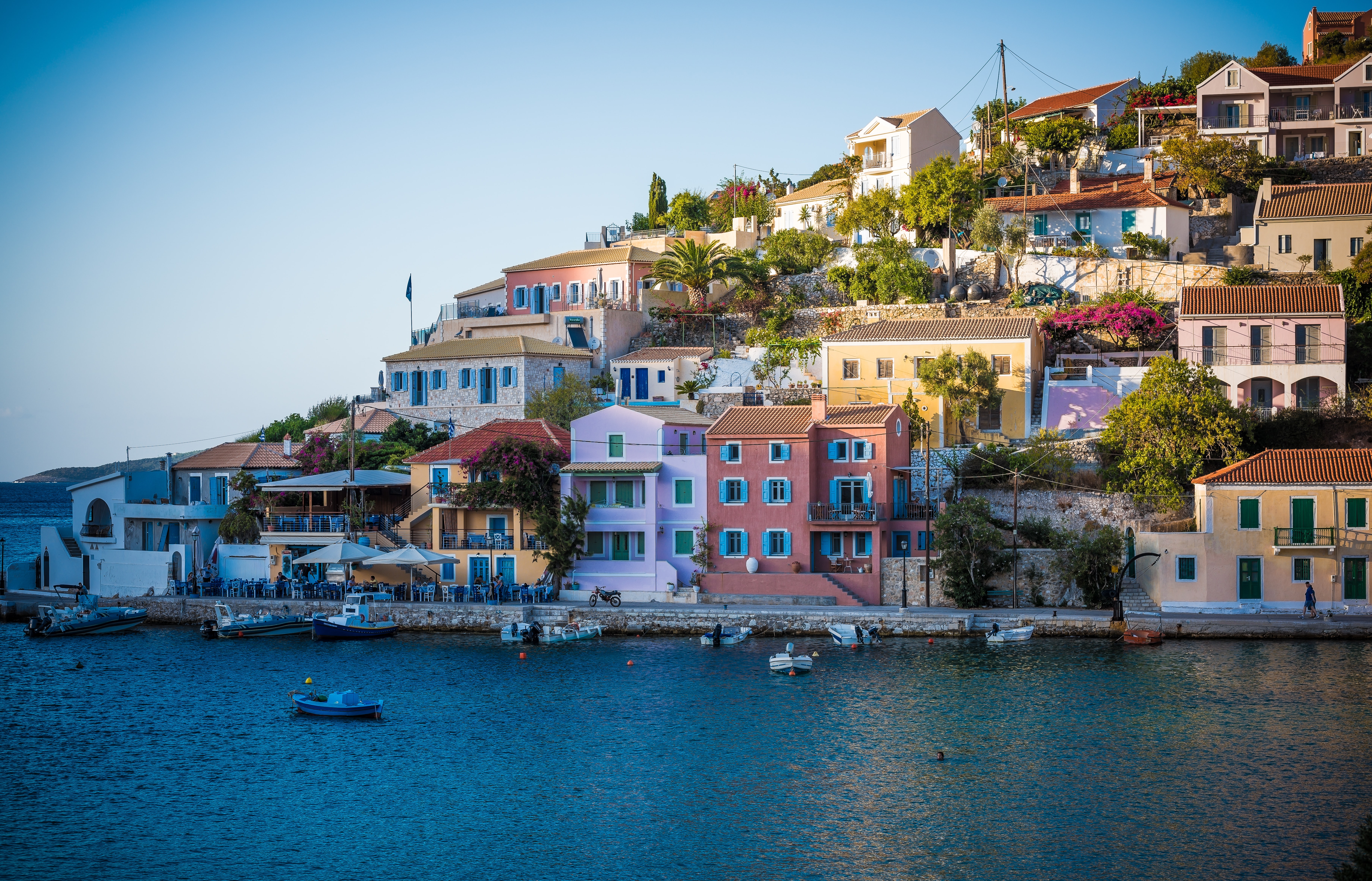colour homes in greece sitting on a hill seaside with boats passing by in asos greece 