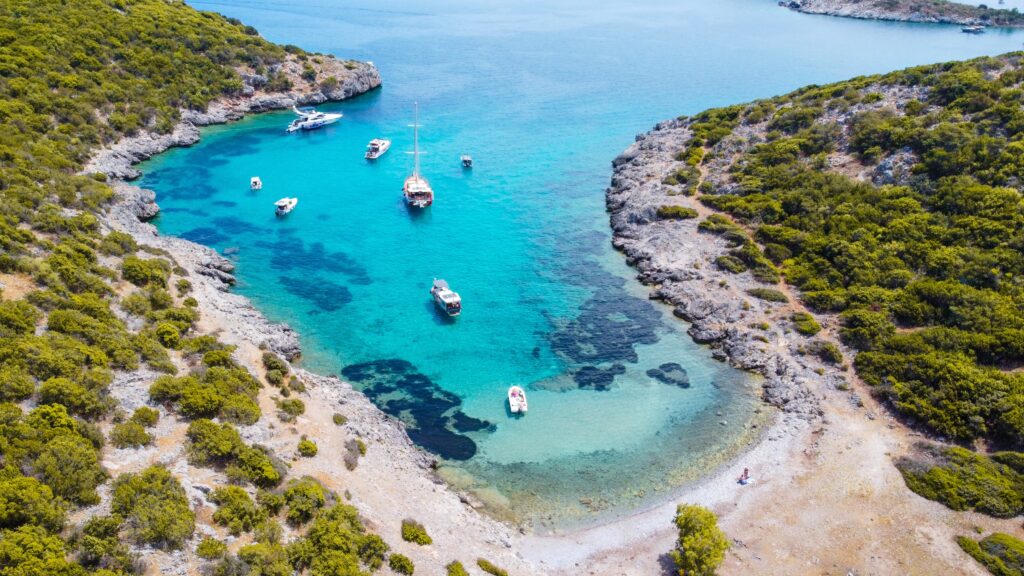 crystal clear pristine water with a few boats sailing at a small intimate shoreline in Bodrum Turkiye 