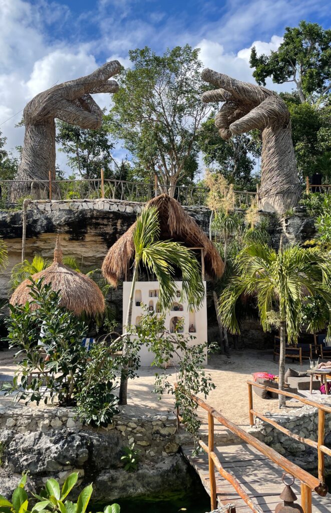 beach club inside of a cenote with large decoration of two hands on the above ground level at casa tortuga cenotes tulum