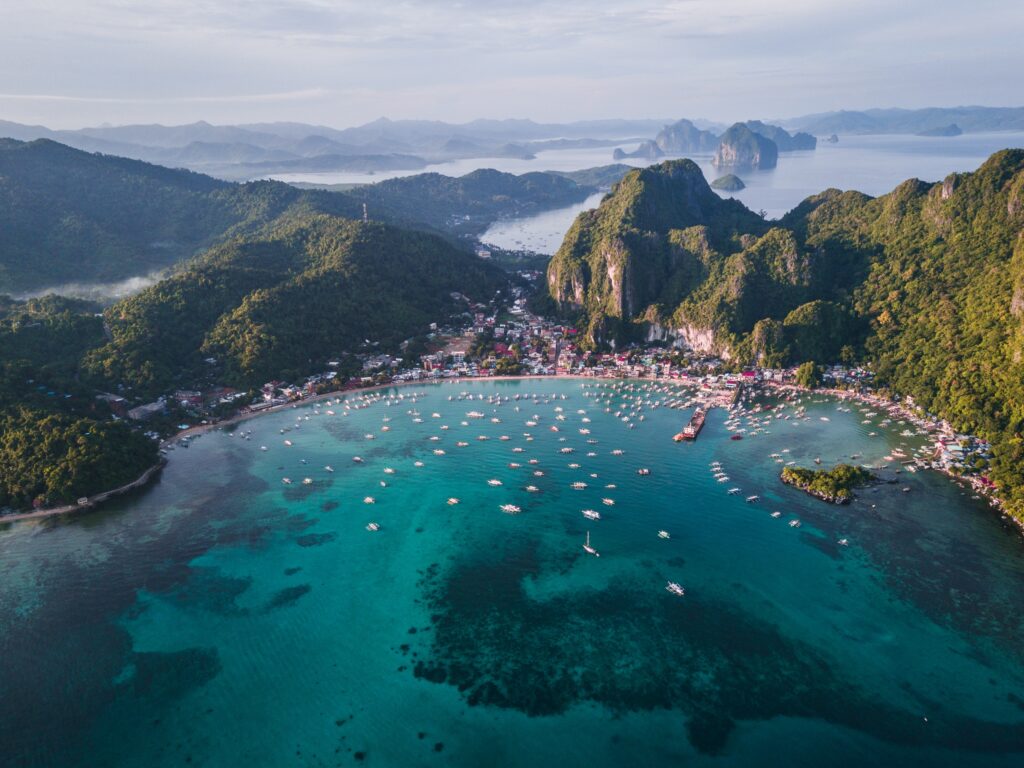 aerial views of the famous el nido beach featuring turquoise blue waters mountains and several boats docks at the shortline 