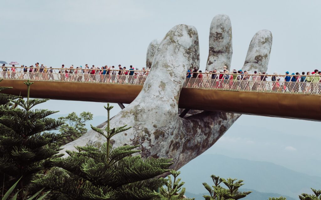 a dense amount of crowd walking along the golden bridge in the ba na hills of vietnam