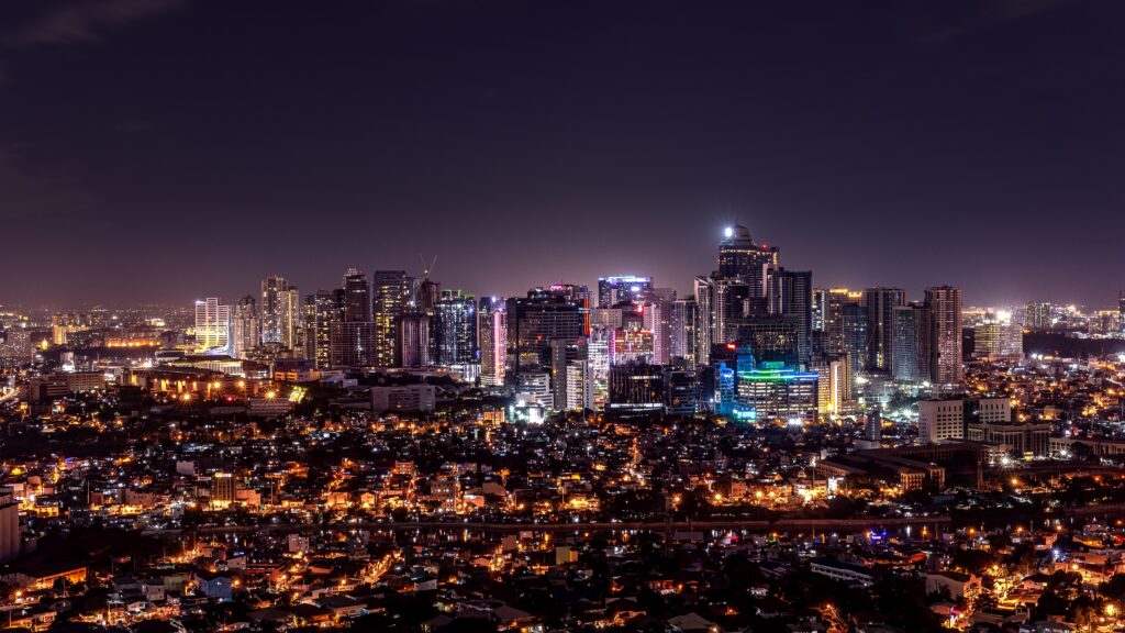 view of metro manila philippines at nighttime with several high town buildings lit up at night