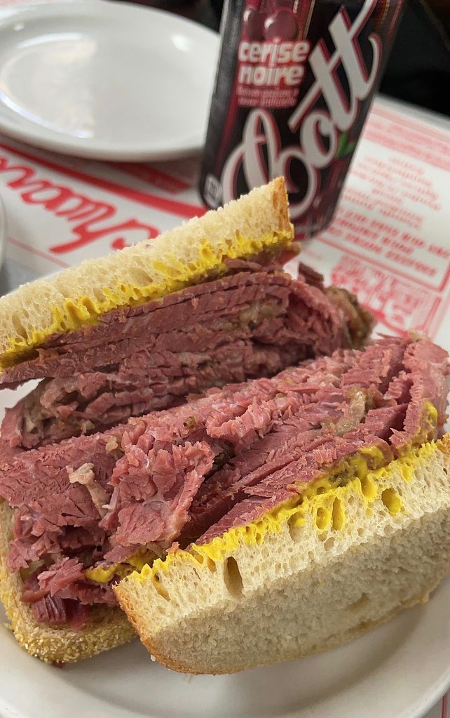 a picture of a smoked meat sandwich from schwartz deli in montreal with a side of local black cherry soda