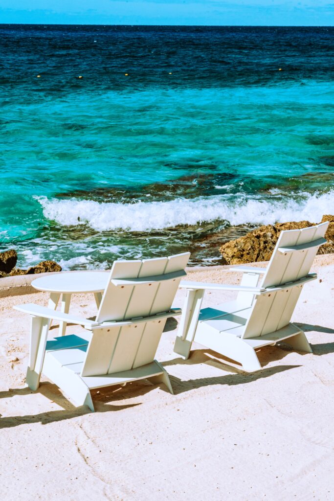 two white beach chairs sitting on a white sandy beach in Cozumel Mexico 