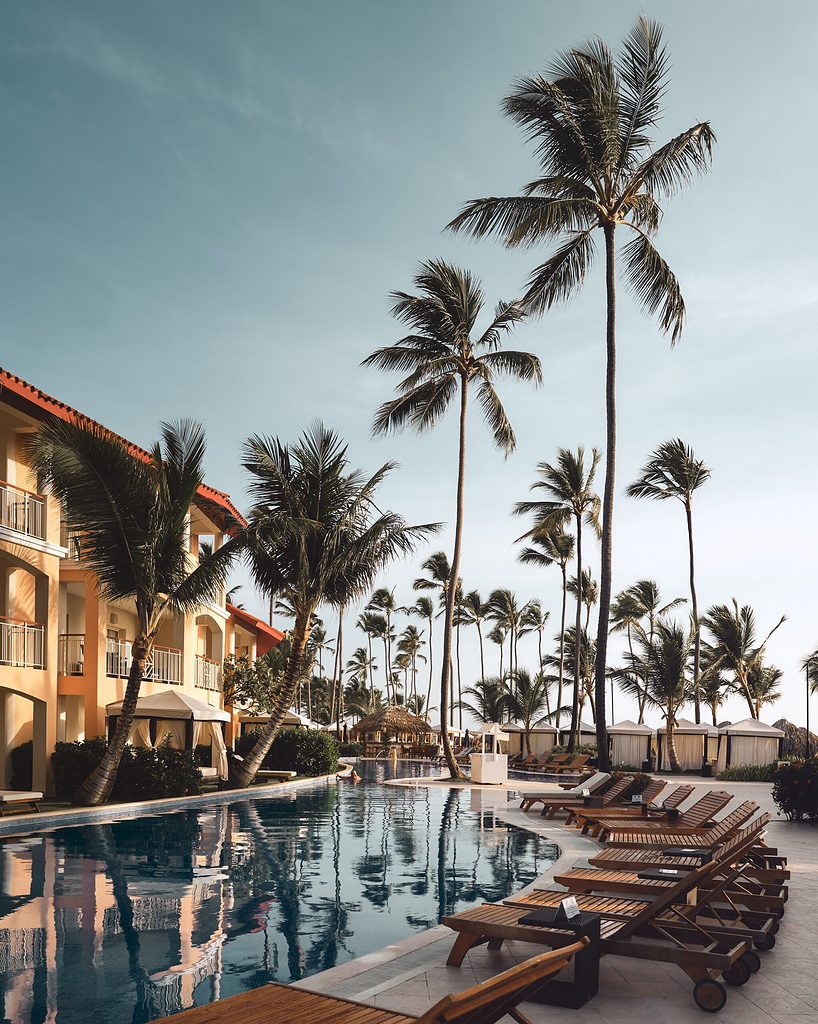 pool side with several palm trees at the marjestic resort in punta cana