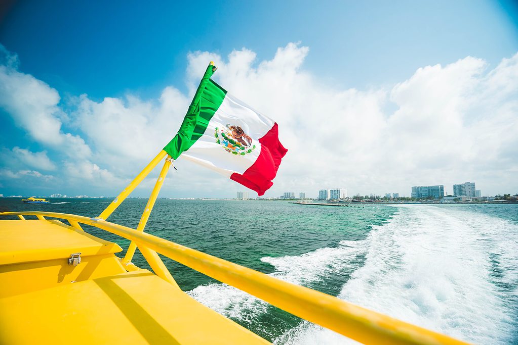Mexican flag hung at the back of a yellow speed boat in the Caribbean sea in Cancun, Mexico