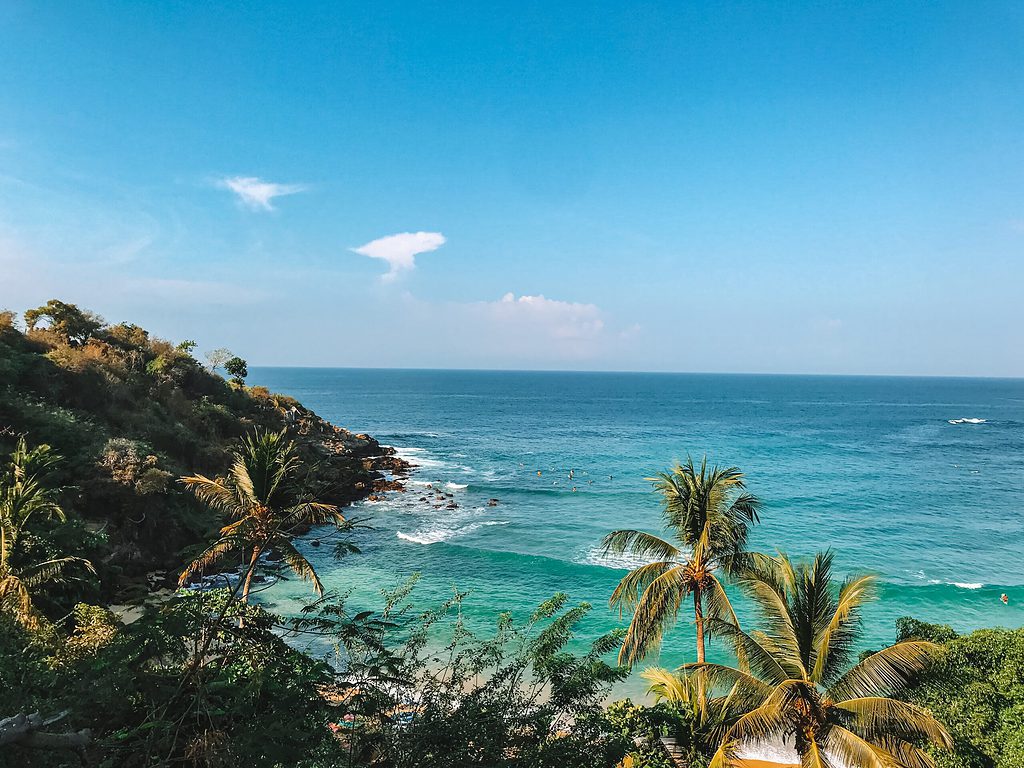 picturesque beach shoreline featuring palm trees, mountains and turquoise waters in Puerto Escondido, Mexico