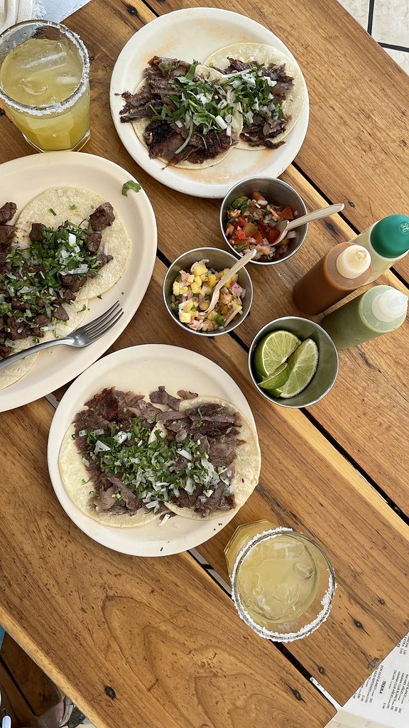 bistec tacos with various hot sauces and glasses of margaritas
