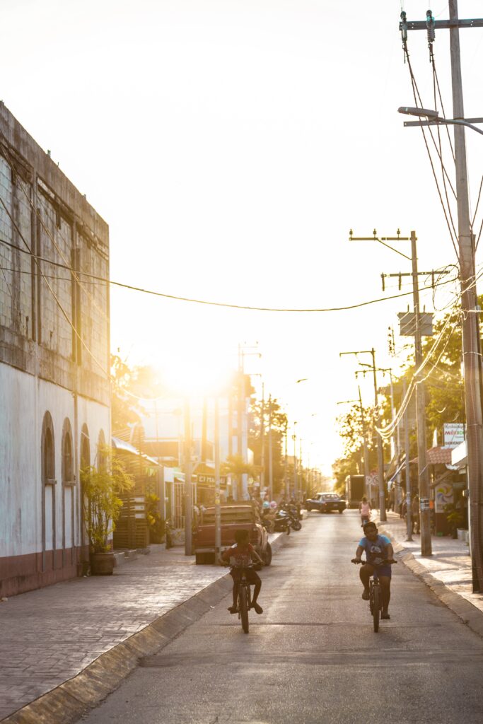 young kids riding their bikes around the streets of Bacalar, Mexico during sunset
