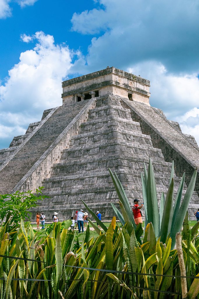 the famous chichen itza pyramid at the ruins along with clear blue skies
