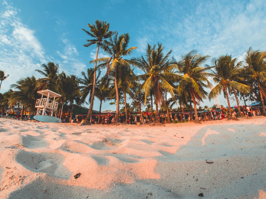 views of the sand and several palm trees on the main strip at Boracay beach in the Philippines 