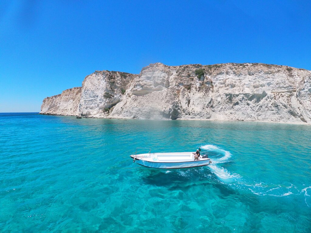 small boat going by in stunning turquoise blue turquoise waters in Crete, Greece