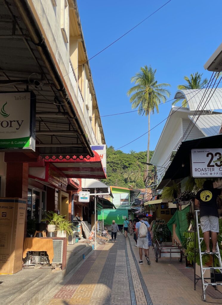 walking street in Phi Phi don with several shops on the side and tourist walking