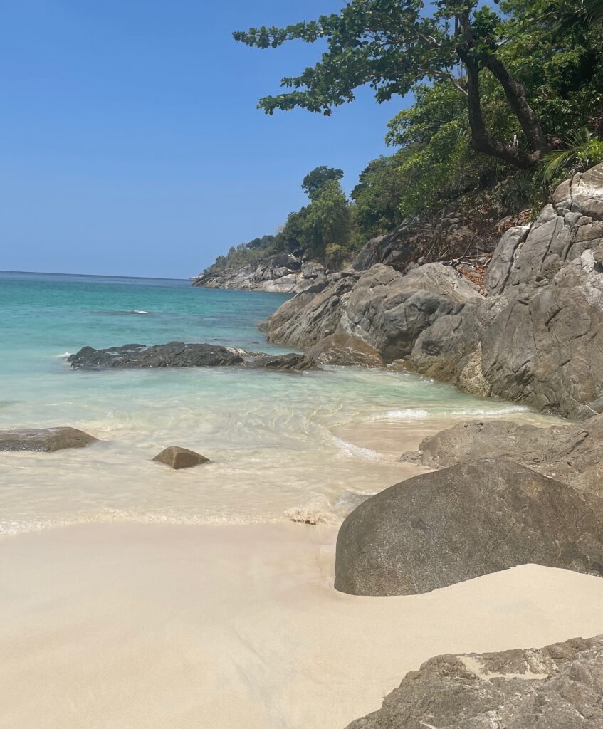 several large rocks and Palm trees on the end of the Hidden Beach area at Freedom Beach in Phuket
