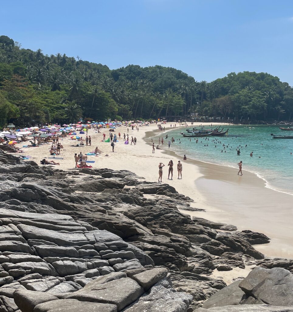 the main beach area at Freedom Beach with several tourists and large rocks separating the main part of Freedom Beach and the hidden beach area