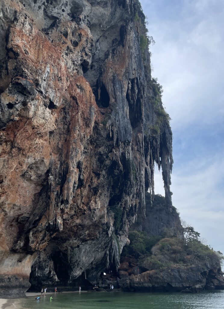 several large rock formations hanging off a cliff and above the water at Phra Nang Cave Beach in Railay