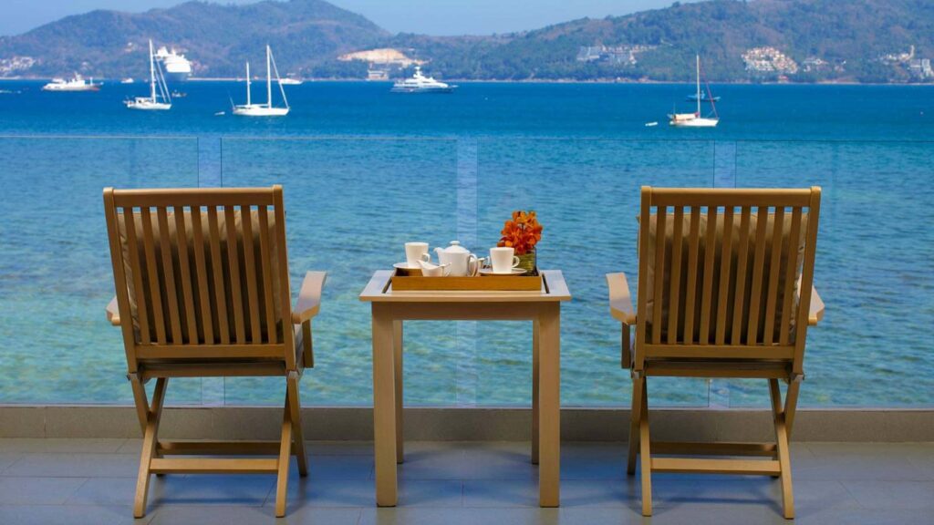 two chairs along side a table with coffee and a few of the ocean and mountainous hills in Patong at the Amari Phuket hotel