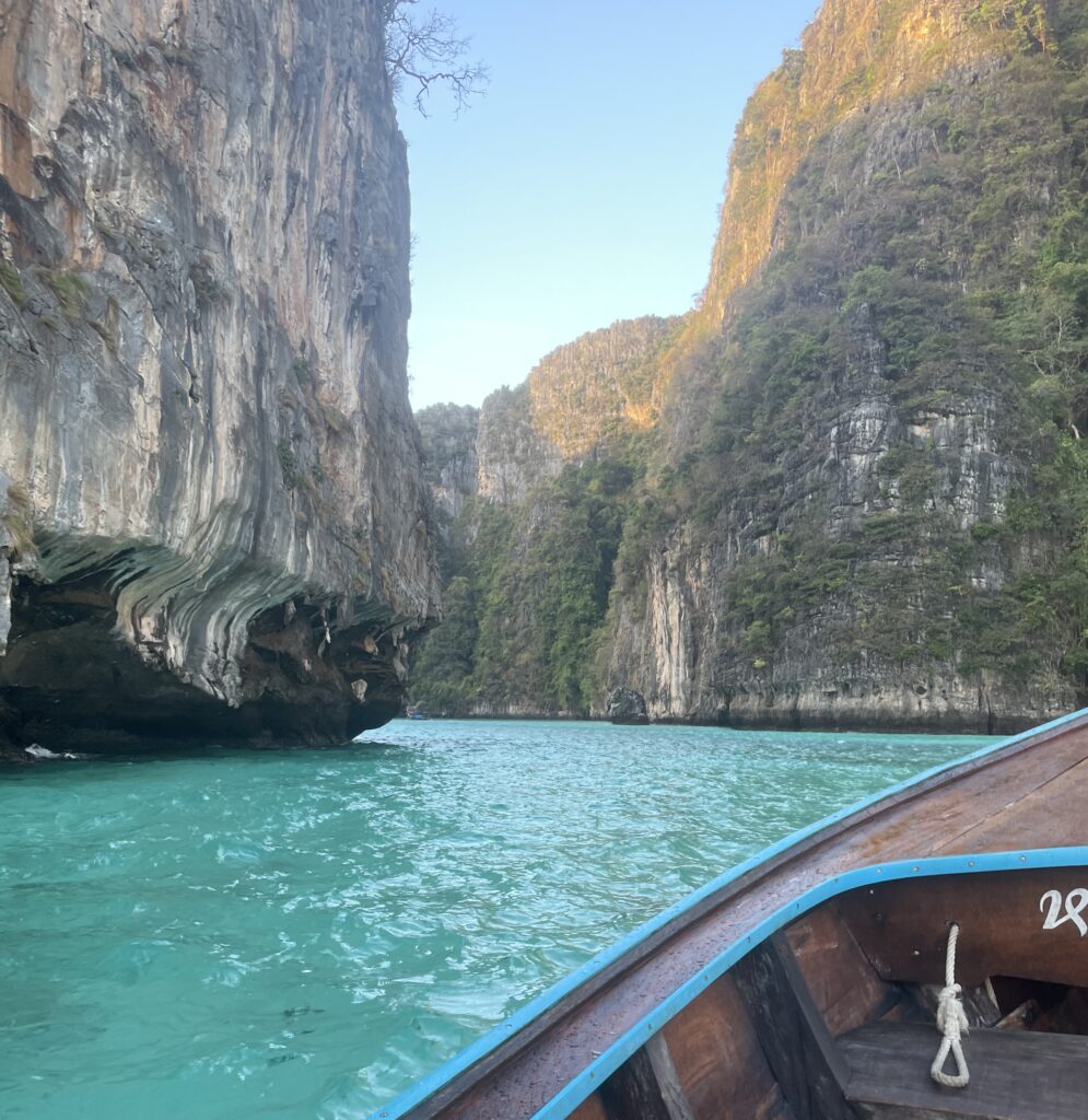 views of giant limestones and beautiful turquoise waters from a long tail boat on the way to Maya Bay Beach in Thailand