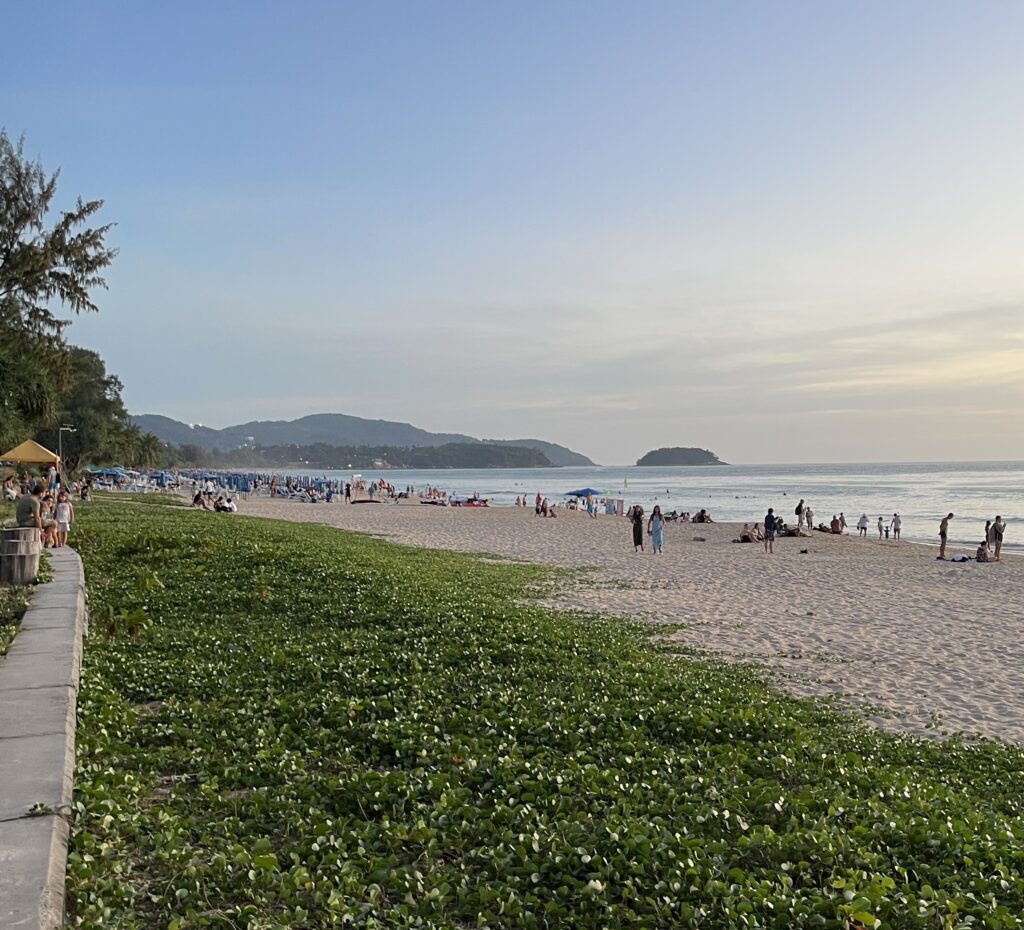 evening time along Karon Beach with tourist on the beach and mountainous range in the distance