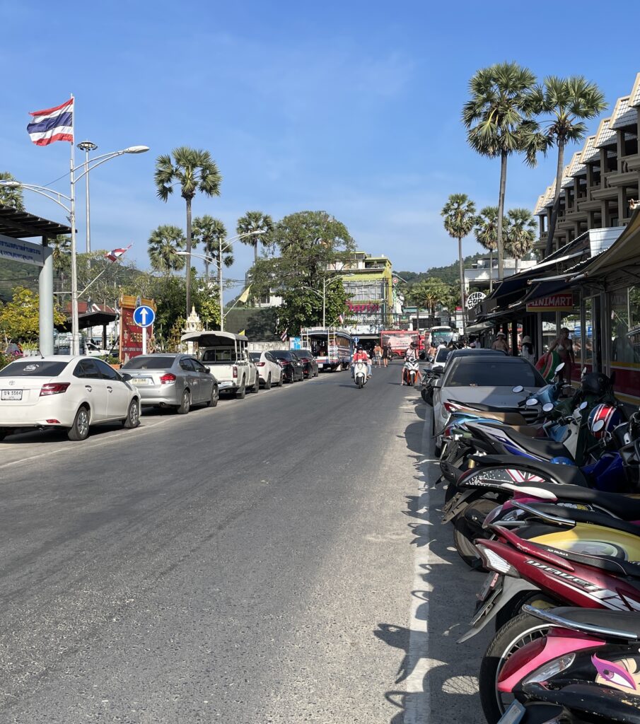 several motorbikes parked on the side of a main road in Kata Beach, Phuket, Thailand