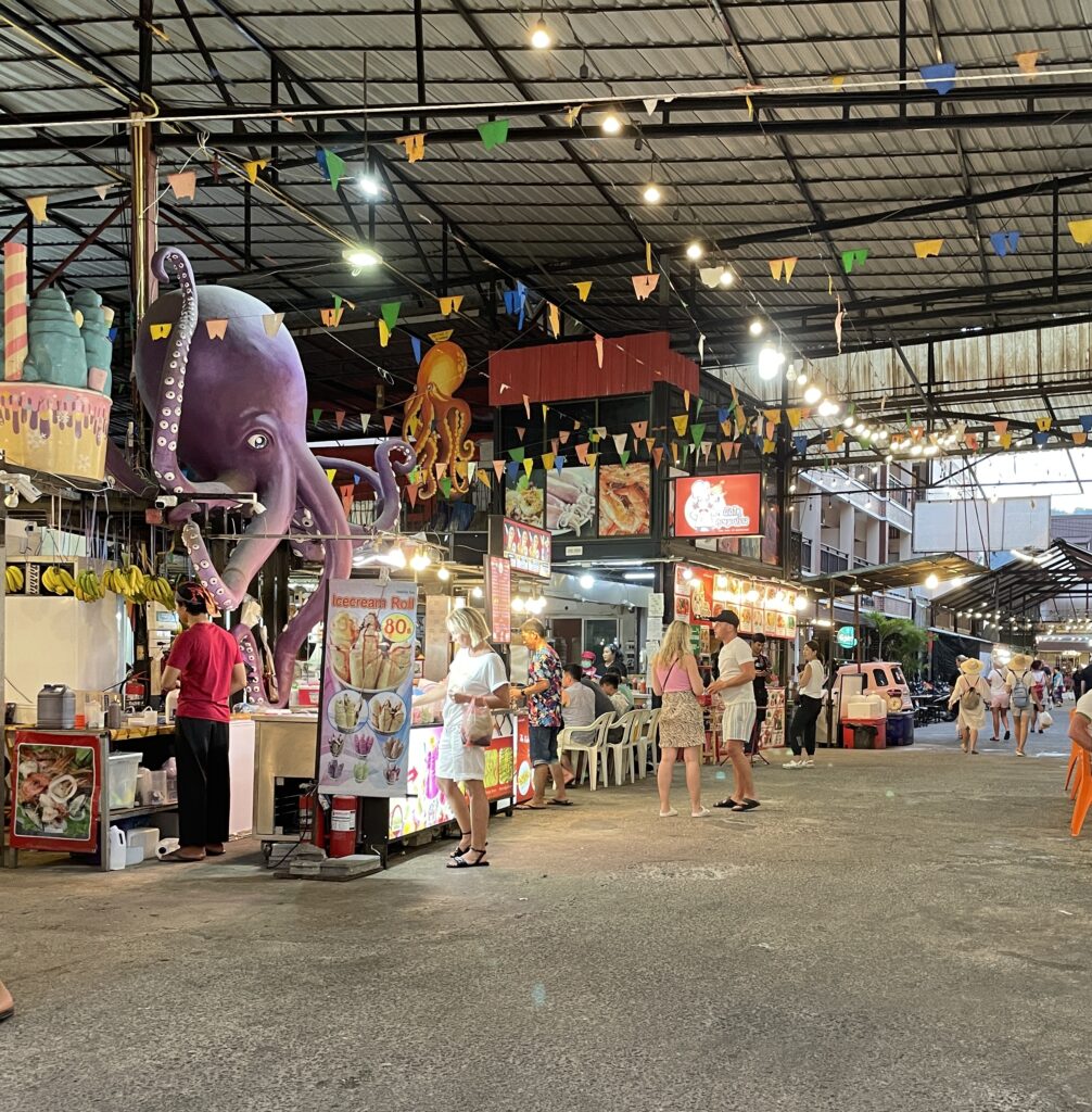 several tourist purchasing food from various food vendors at Kata Night Market in Phuket, Thailand