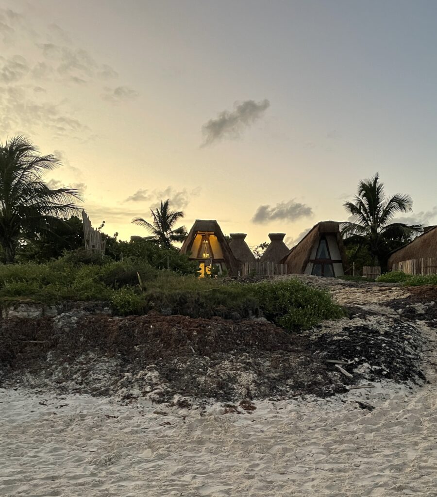 several beach front bohemian styled homes amongst palm trees and the sunset at Tulum North Beach in Mexico / 9 scams in Tulum to avoid