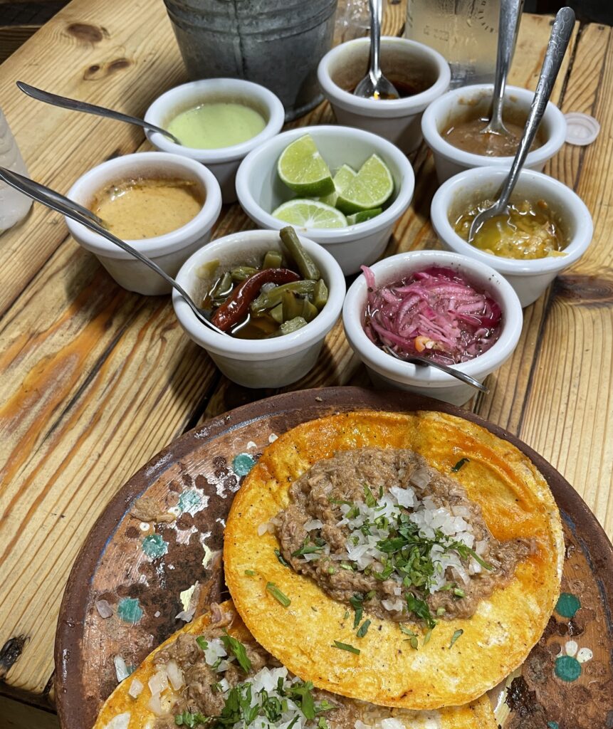 birria tacos with several side garnish being served at Birria de la 30 in Playa Del Carmen 