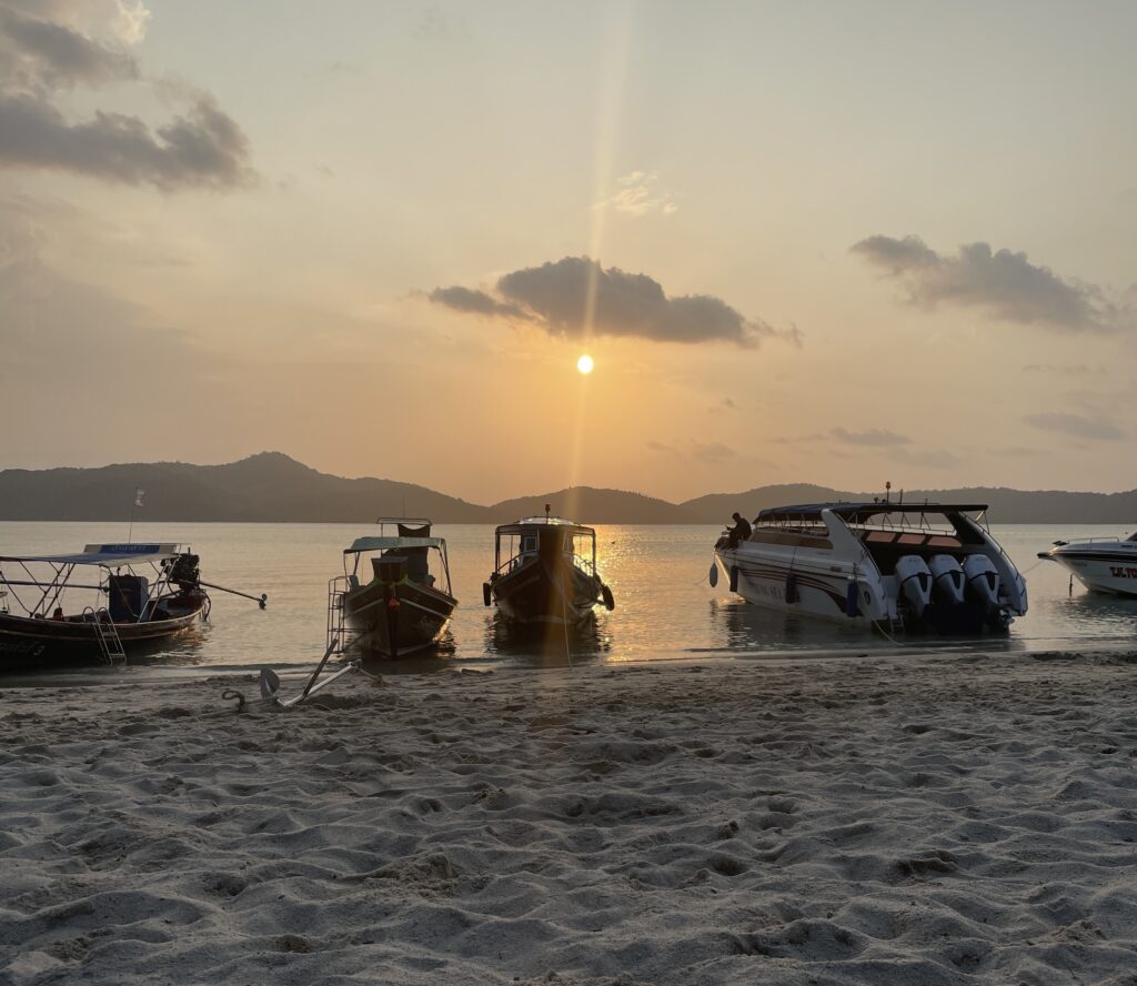 beach at sunset with several boats anchored at Ko Mat Sum island, also known as Pig Island