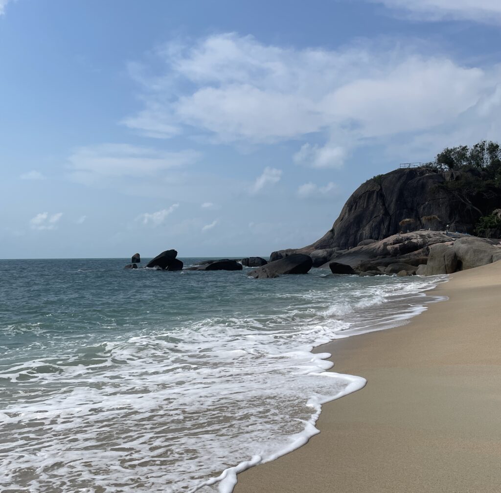 clear sand, foamy ocean water and large rocks at the end of the shoreline at Lamai Beach in Koh Samui / Is Koh Samui worth visiting