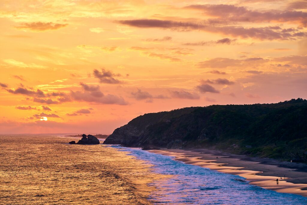 vibrant sunset of many colours setting in amongst the shores and high cliffs in Mazunte, Mexico