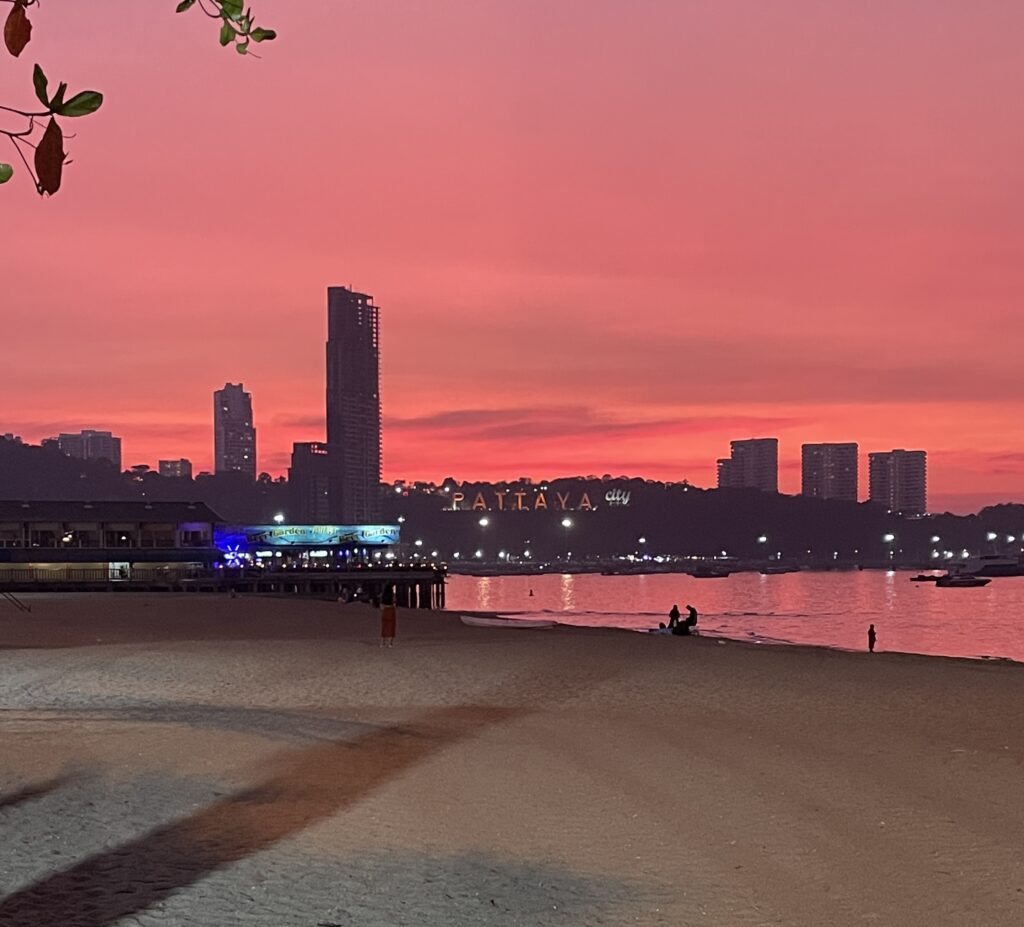 stunning orange sunset at Pattaya Beach with skyscrappers in the distance among the Pattaya City sign