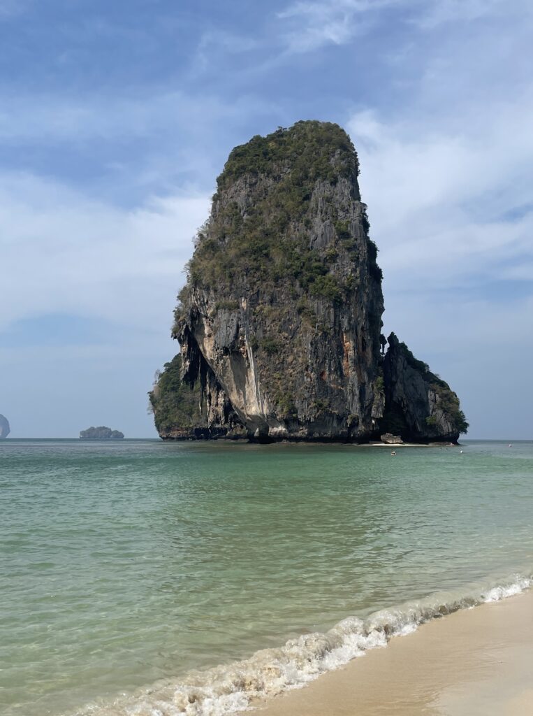 large limestone isolated in the ocean being views from Phra Nang Cave Beach in Railay, Krabi, Thailand