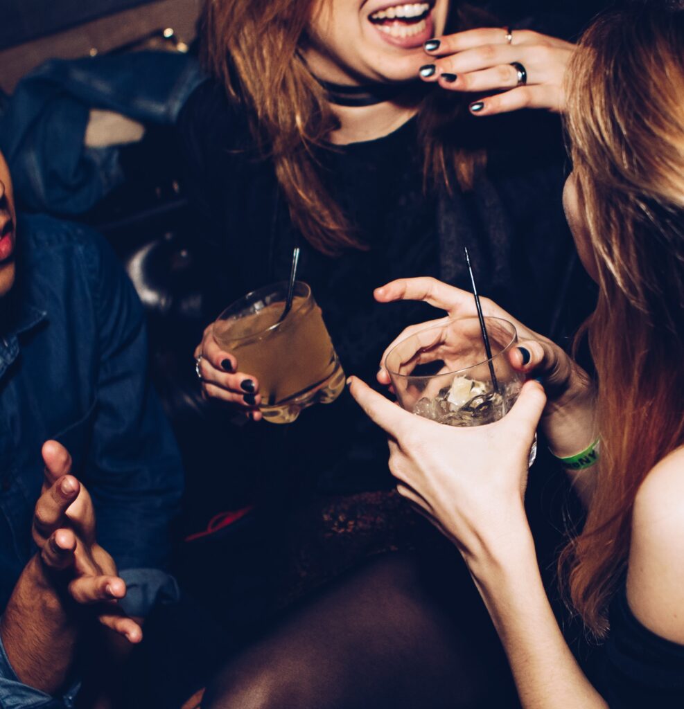 two woman laughing and enjoying drinks inside of a bar 