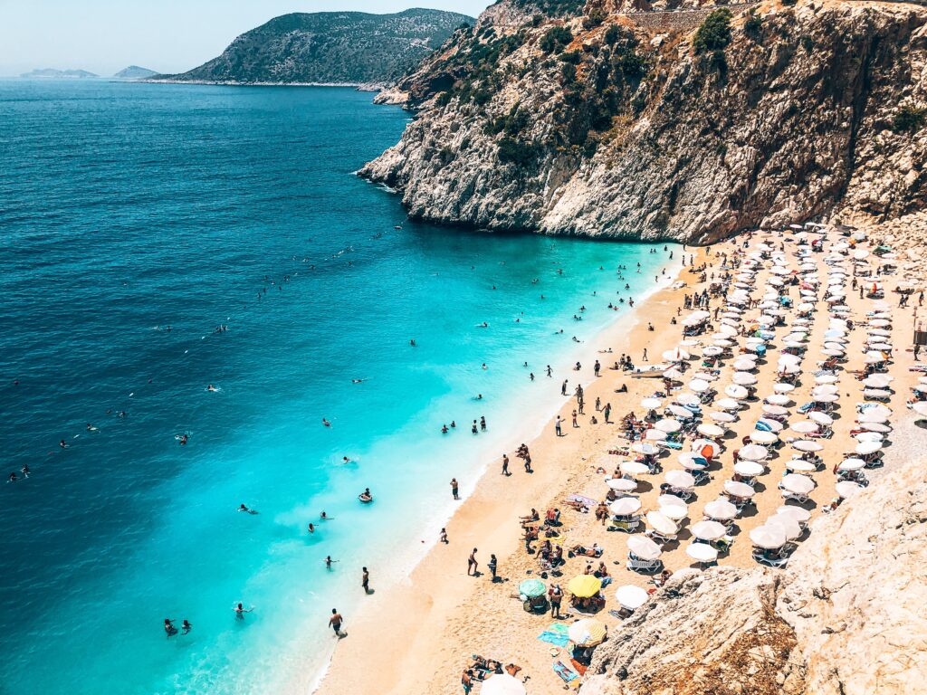 crystal clear shades of blue water on a beach shoreline full of tourist in Antalya, Turkey