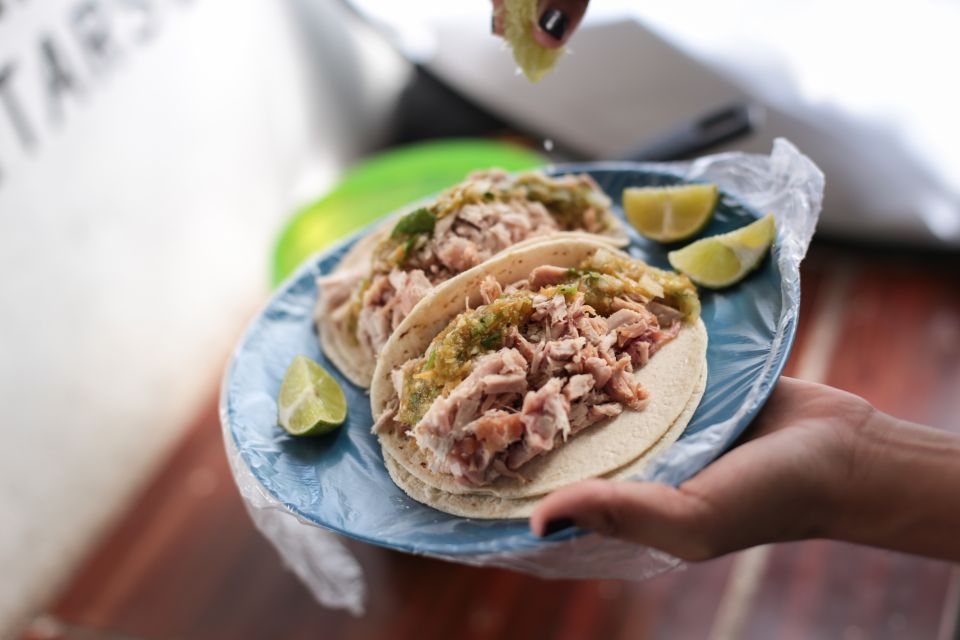 chicken tacos on a plastic plate and lime being squeezed on top of during one of the best Cancun Food Tours 