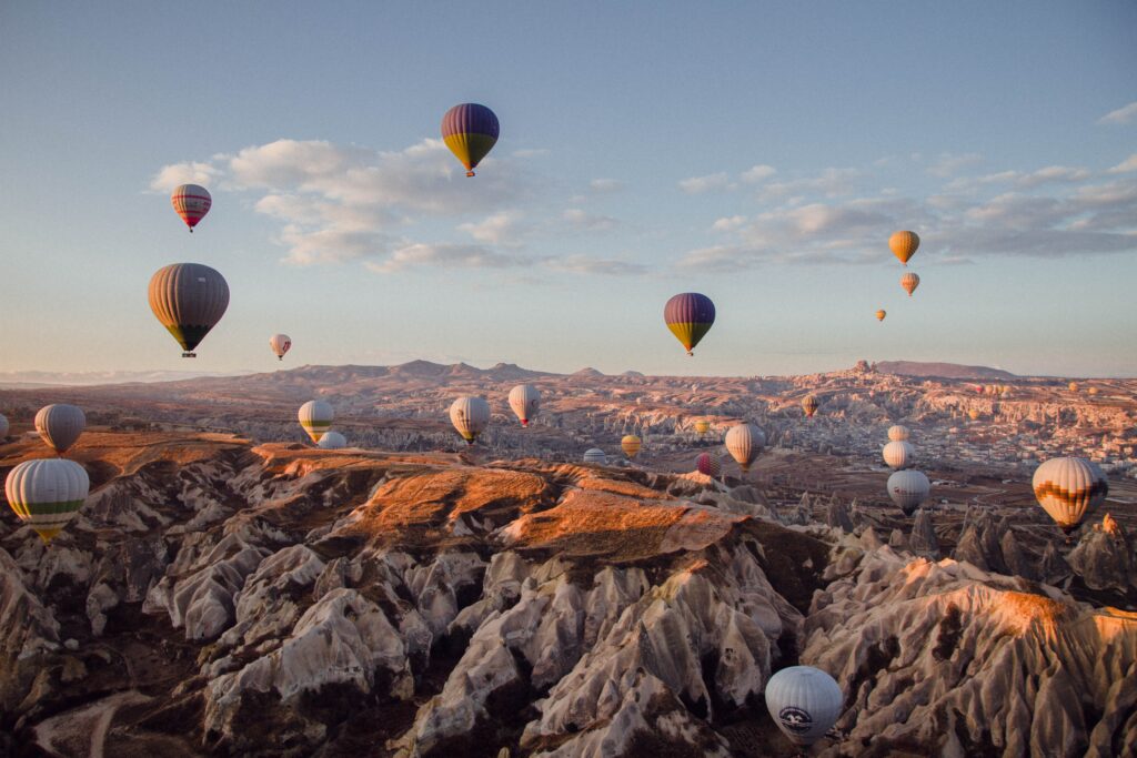 several hot air balloons flying amongst the picturesque rocky landscape in Cappadocia, Turkey 