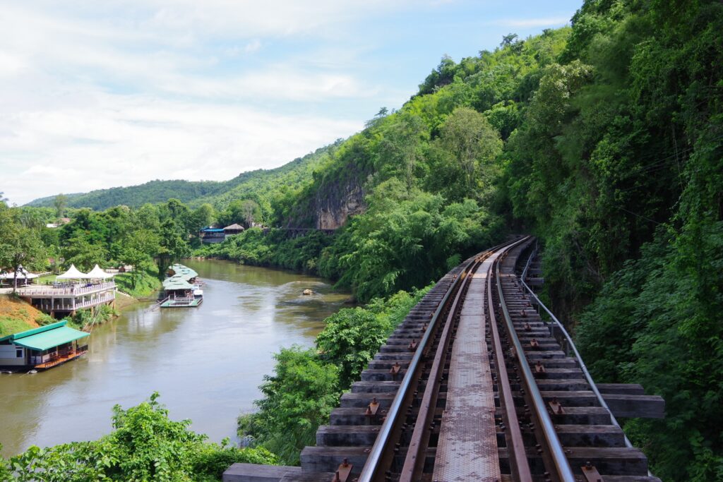 train track along luscious green forest and the river in Kanchanaburi, Thailand