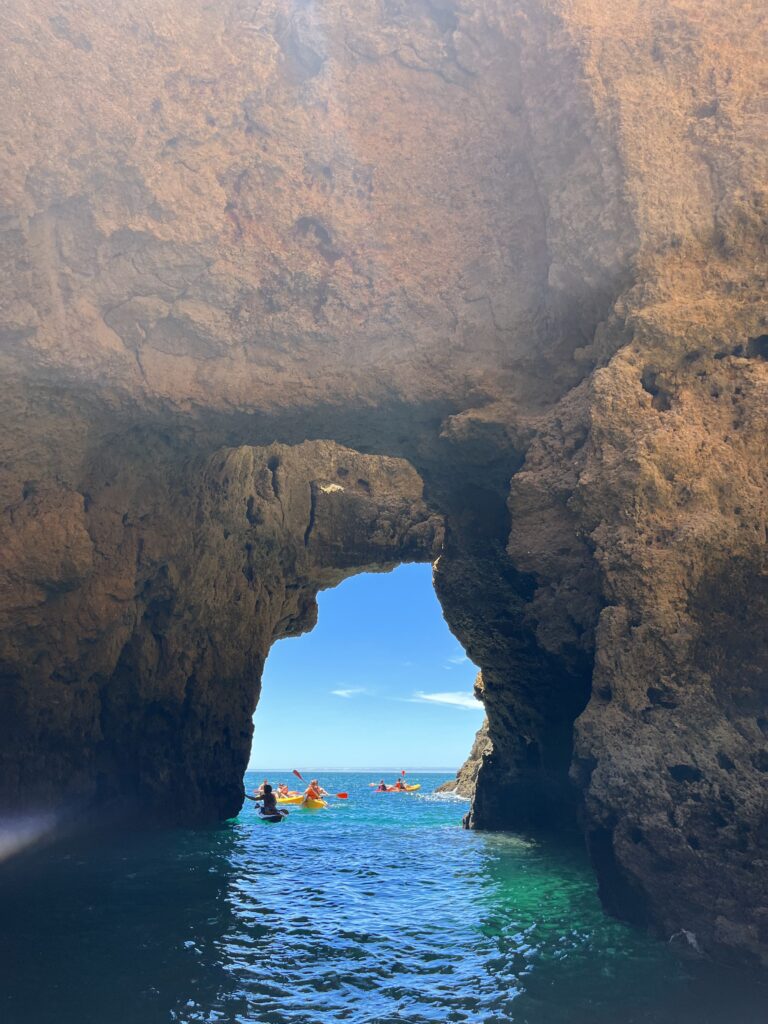 several tourists kayaking through the many rock formations in the waters of Lagos, Portugal