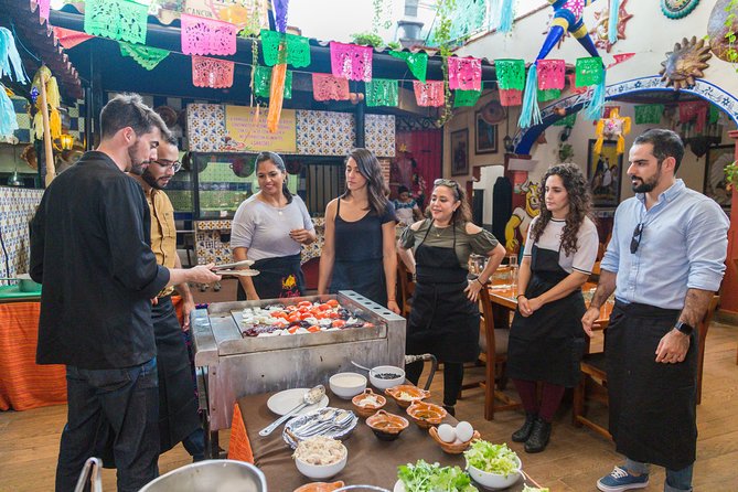 several tourists gathered around being taught how to make a dish during a Mexican cooking class in Cancun, Mexico