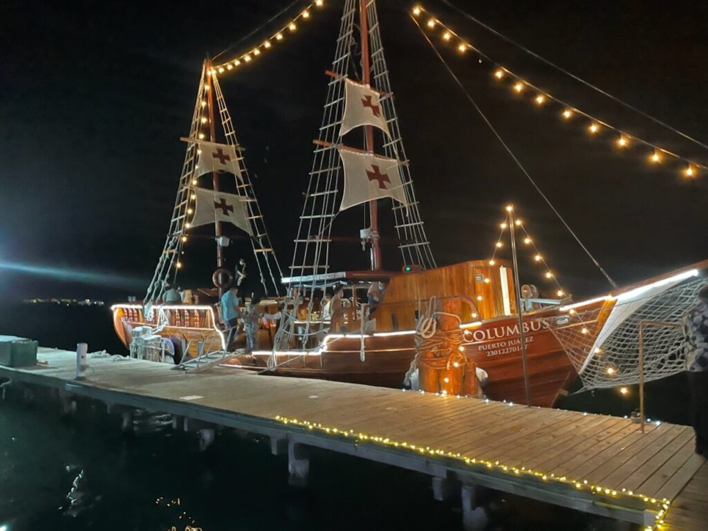 large wooden sailboat with many lights and decorations docked in Cancun, Mexico