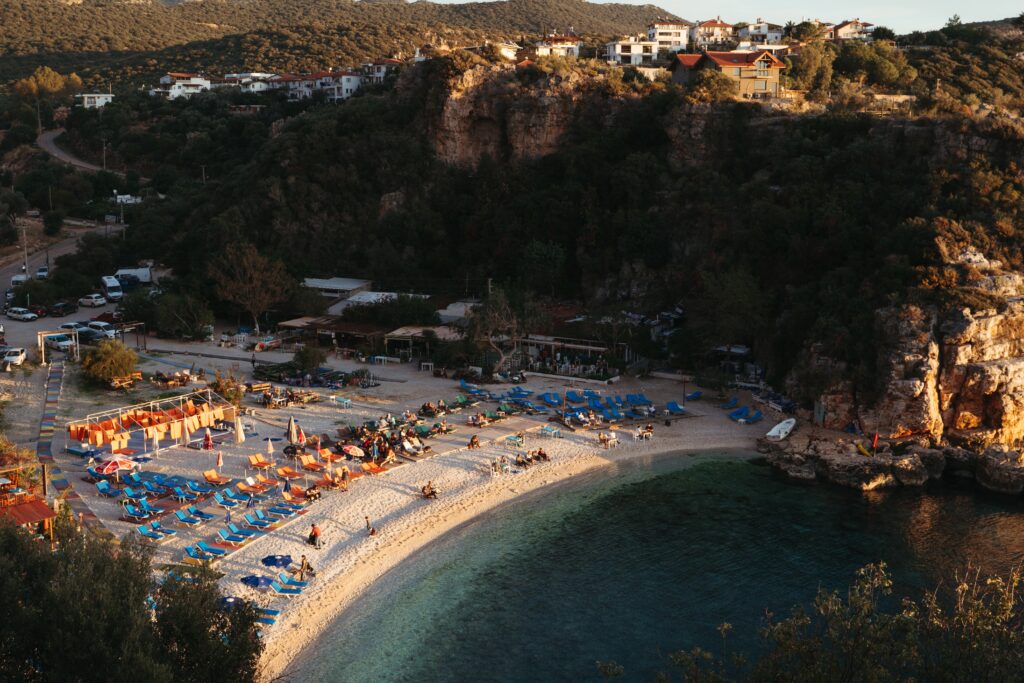 small beach shoreline full of tourist sunbathing between two cliffs in Kas, Turkey