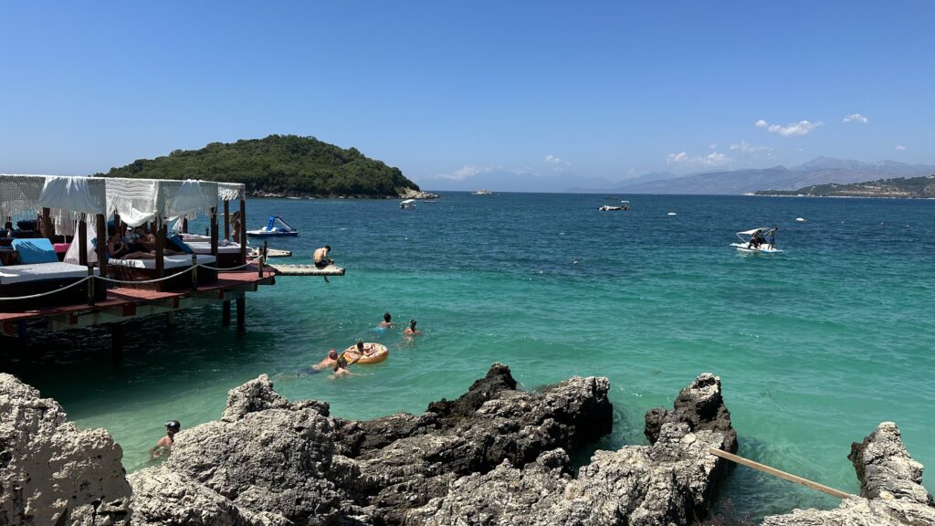 colourful shades of blue water and an island in the distance at Ksamil Beach