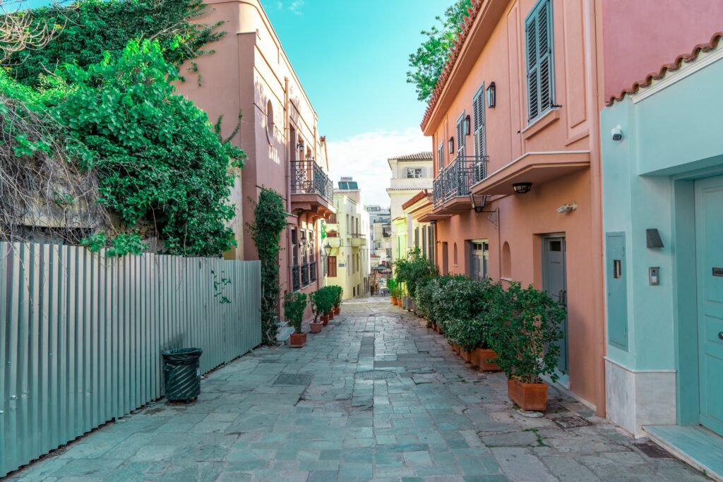 empty cobblestone street in Athens full of beautiful pastel coloured homes and plants  